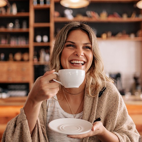 Woman smiling while enjoying coffee at restaurant