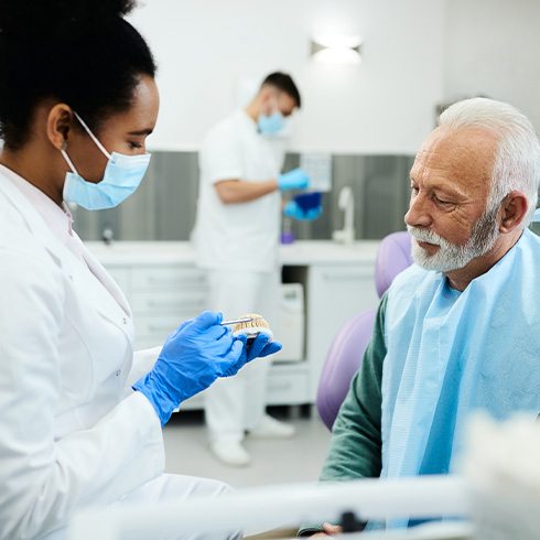 A dentist showing a denture to her patient