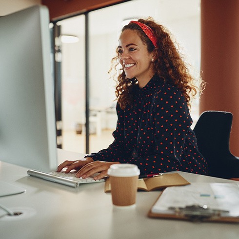 Woman smiling while working on computer in office