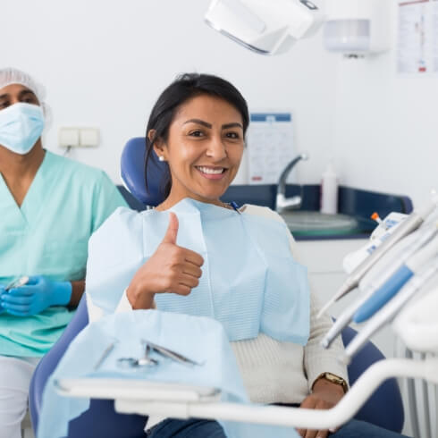 Woman in dental chair giving thumbs up