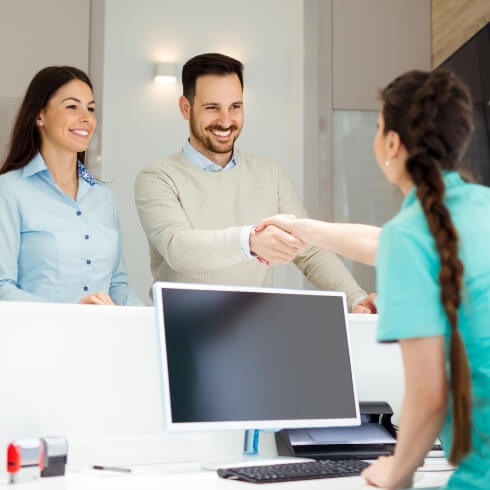 Dental team member shaking hands with dentistry patients