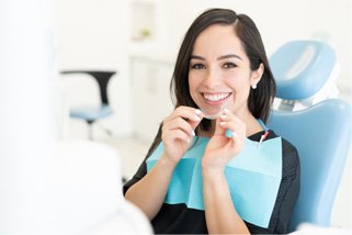 A man calculating the cost of dental crowns with a calculator, coins, and a tooth model