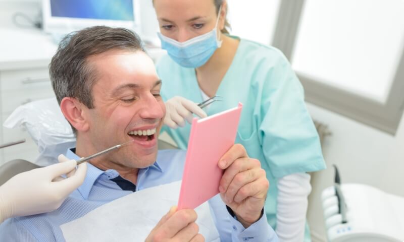Man looking at smile after receiving dental bridges