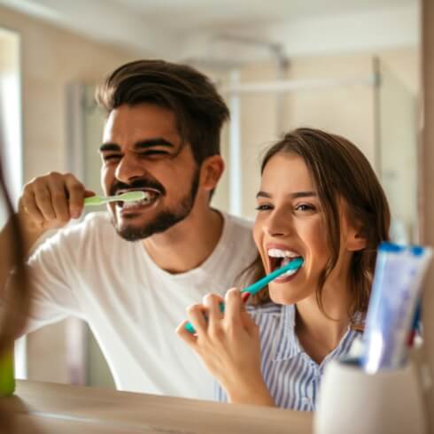 Man and woman brushing teeth to prevent dental emergencies