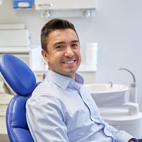 Male dental patient sitting in dental chair and smiling