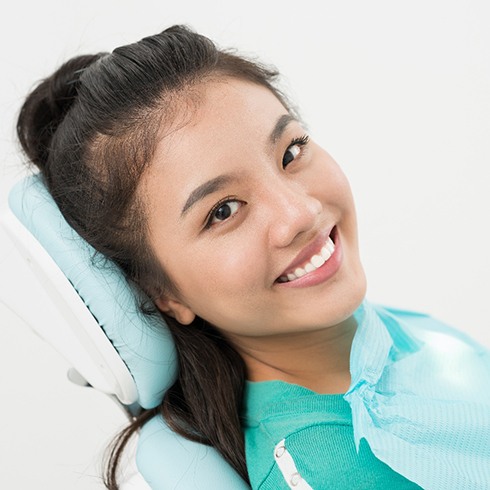 Female patient sitting back in dental chair smiling