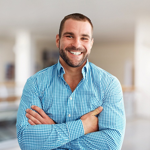 Man in blue shirt smiling with his arms crossed