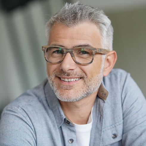 Man with glasses sitting down and smiling