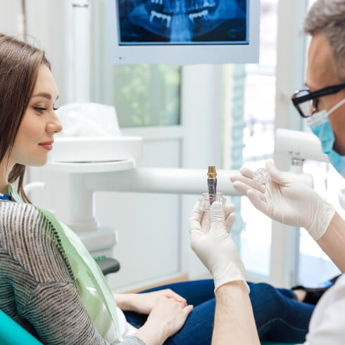 Dentist and dental patient looking at dental implant model