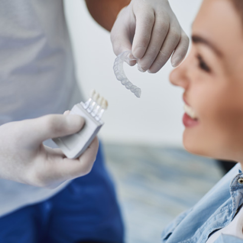 A dentist showing an Invisalign tray to a young woman 