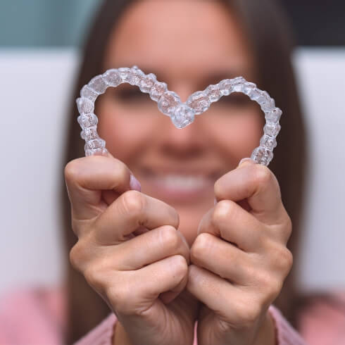 Person holding to clear correct aligner trays up to create a heart shape