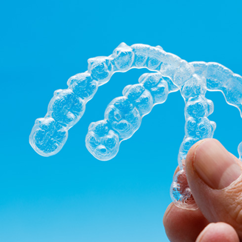 Man holding set of Invisalign trays 