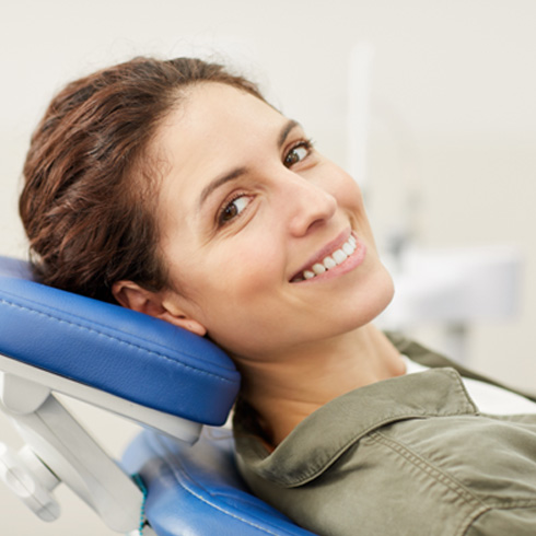 Woman lying back in dental chair smiling
