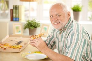 Smiling senior man enjoying a slice of pizza