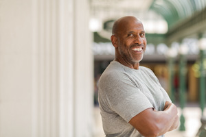 Man in grey shirt smiling with his arms folded