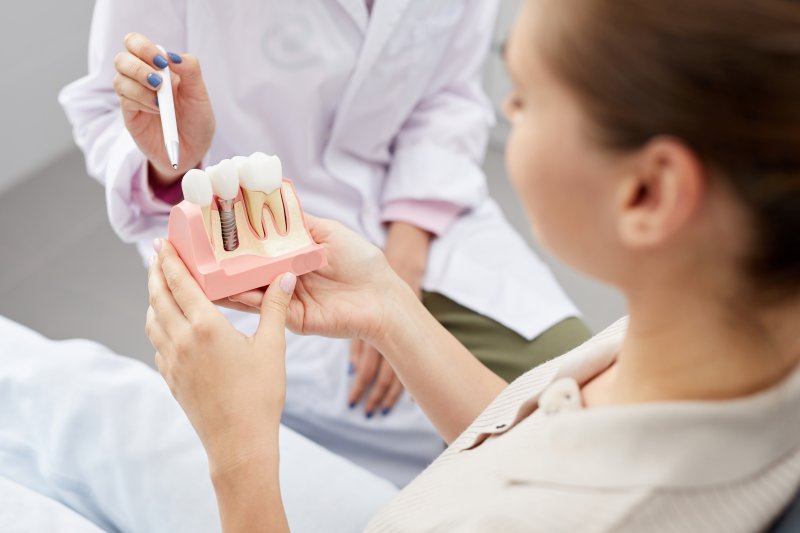 A dental patient holding an enlarged model of dental implant