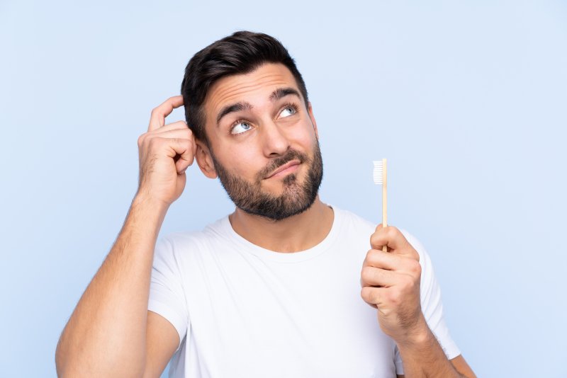 Patient with dental implants pondering with toothbrush
