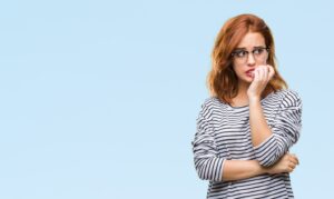 Worried-looking woman chewing on a fingernail.